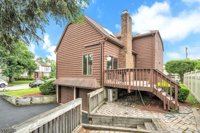 23 Bohnert Pl, Waldwick Boro, NJ 07463 - rear view of property featuring a chimney, asphalt driveway, an attached garage, a wooden deck, and stairs
