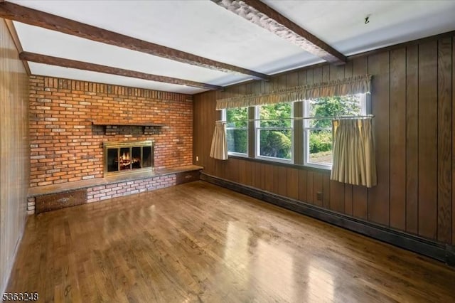 45 Churchill Rd, Cresskill Boro, NJ 07626 - unfurnished living room featuring beam ceiling, wood finished floors, a brick fireplace, wood walls, and baseboard heating