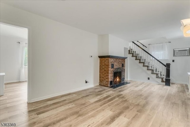14 Prospect Pl, Morris Twp, NJ 07960 - unfurnished living room featuring light wood finished floors, a brick fireplace, a wall mounted air conditioner, and stairway