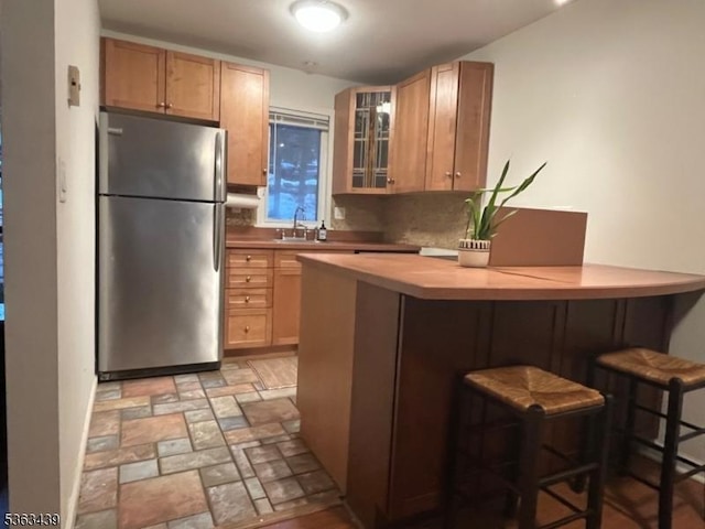 17 Village Way Unit 4, Vernon Twp, NJ 07462 - kitchen featuring freestanding refrigerator, a kitchen bar, a peninsula, glass insert cabinets, and light countertops