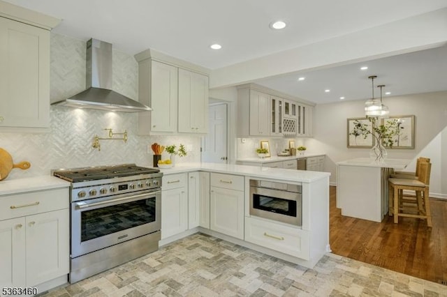 26 Brockden Dr, Mendham Twp, NJ 07945 - kitchen featuring wall chimney range hood, gas range, light countertops, a peninsula, and glass insert cabinets