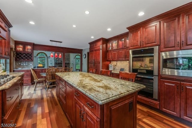 4 Fisher Ct, Raritan Twp, NJ 08822 - kitchen featuring stainless steel appliances, reddish brown cabinets, a center island, dark wood finished floors, and tasteful backsplash