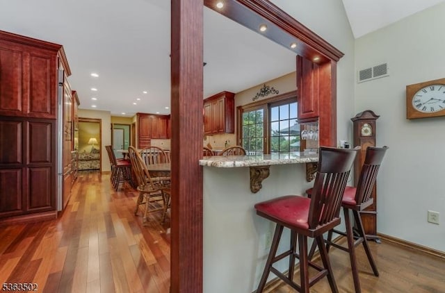 4 Fisher Ct, Raritan Twp, NJ 08822 - kitchen with dark brown cabinets, wood finished floors, light stone counters, a breakfast bar, and recessed lighting