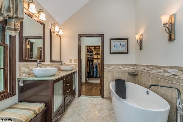 4 Fisher Ct, Raritan Twp, NJ 08822 - bathroom featuring lofted ceiling, a freestanding tub, double vanity, tile walls, and a walk in closet