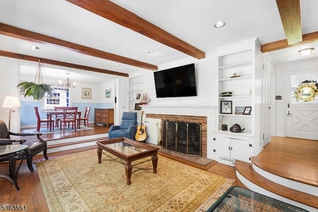 12 Schoolhouse Ln, Morris Twp, NJ 07960 - living area featuring wood finished floors, built in shelves, a brick fireplace, a chandelier, and beamed ceiling