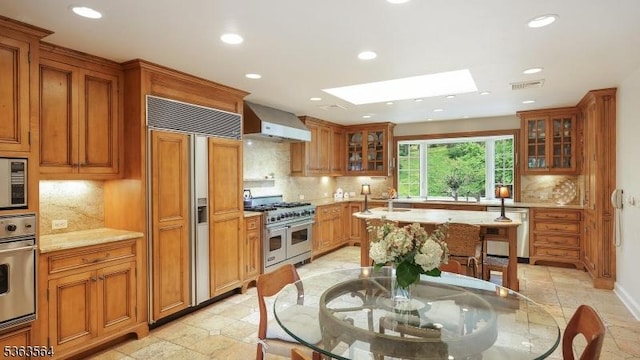 80 Clark Rd, Bernardsville Boro, NJ 07924 - kitchen featuring high end appliances, wall chimney exhaust hood, a skylight, recessed lighting, and brown cabinetry