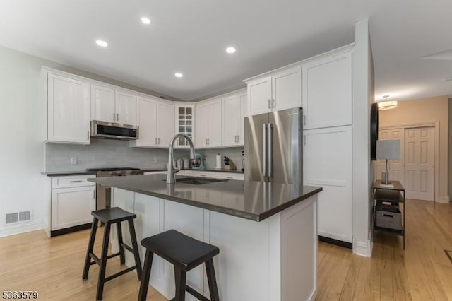 22 La Costa Dr, Clinton Twp, NJ 08801 - kitchen with appliances with stainless steel finishes, dark countertops, light wood-type flooring, a breakfast bar area, and recessed lighting