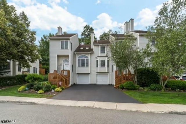 32 Ryan Ln, Lincoln Park Boro, NJ 07035 - townhome / multi-family property with a garage, driveway, stairs, a chimney, and stucco siding