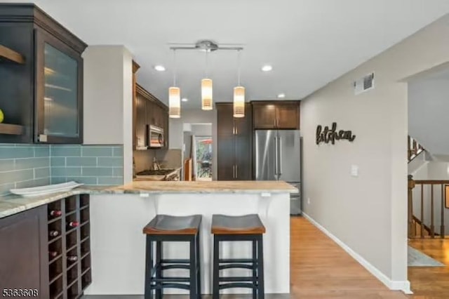 32 Ryan Ln, Lincoln Park Boro, NJ 07035 - kitchen with stainless steel appliances, a kitchen breakfast bar, light countertops, light wood-style floors, and tasteful backsplash