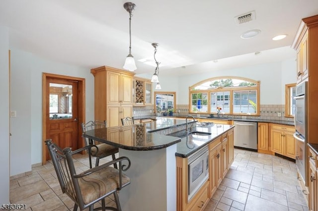 44 Shetland Dr, Clark Twp, NJ 07066 - kitchen with appliances with stainless steel finishes, a kitchen bar, decorative backsplash, a center island with sink, and stone tile floors