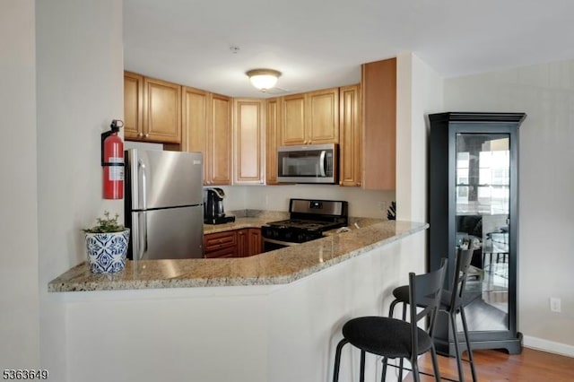 1111 Worthington Ct, Denville Twp, NJ 07834 - kitchen featuring stainless steel appliances, wood finished floors, light stone countertops, a breakfast bar area, and a peninsula