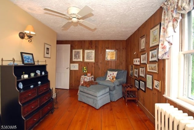 1135 State Route 28, Branchburg Twp, NJ 08876 - living area featuring radiator, wood walls, a textured ceiling, a ceiling fan, and light wood-style flooring
