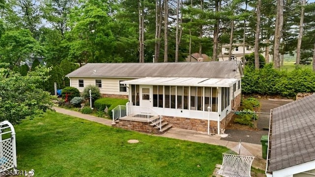 16 Hazen Rd, Mansfield Twp, NJ 07840 - rear view of house with a lawn, a sunroom, view of scattered trees, and stone siding