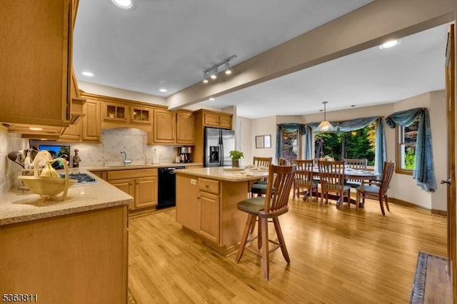 214 Glenside Pl, North Plainfield Boro, NJ 07060 - kitchen featuring stainless steel fridge, black dishwasher, light wood-style flooring, a breakfast bar area, and a center island