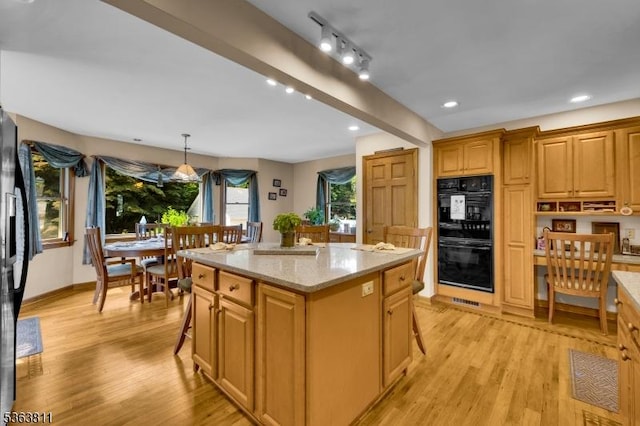 214 Glenside Pl, North Plainfield Boro, NJ 07060 - kitchen featuring black appliances, a breakfast bar area, light wood-style flooring, a center island, and light stone counters