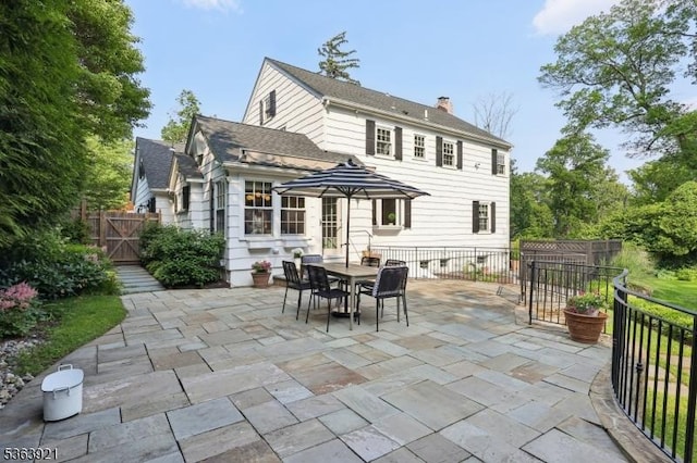 75 Farley Rd, Millburn Twp, NJ 07078 - back of property with a patio, a chimney, a gate, outdoor dining area, and a shingled roof
