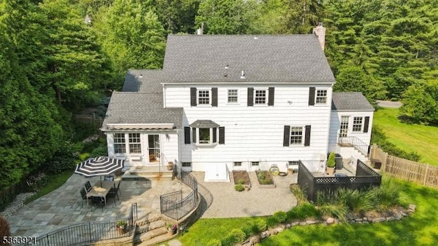 75 Farley Rd, Millburn Twp, NJ 07078 - rear view of property featuring a patio, a chimney, a fenced backyard, a garden, and a shingled roof
