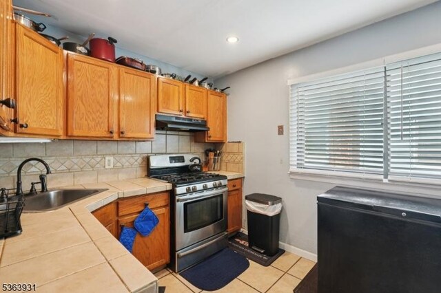 9 Lee Ct, Maplewood Twp, NJ 07040 - kitchen featuring gas stove, under cabinet range hood, tile countertops, tasteful backsplash, and light tile patterned floors