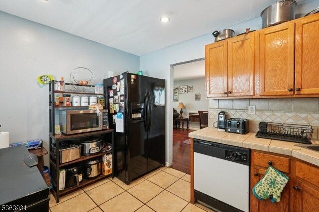 9 Lee Ct, Maplewood Twp, NJ 07040 - kitchen with dishwasher, black fridge with ice dispenser, stainless steel microwave, tile countertops, and light tile patterned floors