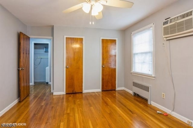 24 Hutton Ave Unit 46, West Orange Twp, NJ 07052 - unfurnished bedroom featuring radiator, wood finished floors, a wall mounted AC, and ceiling fan