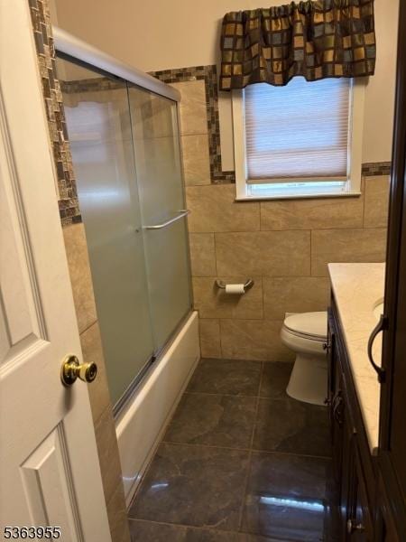85 Stonehenge Ter, Clark Twp, NJ 07066 - bathroom featuring vanity, tile walls, combined bath / shower with glass door, tile patterned flooring, and a wainscoted wall