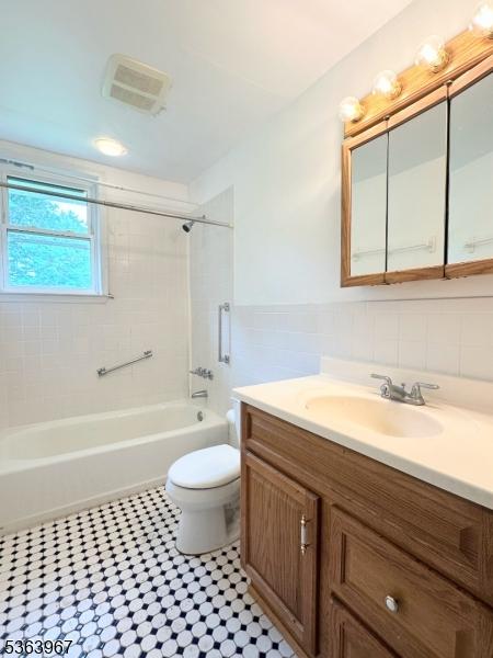 30 Bennington Pkwy, Franklin Twp, NJ 08823 - full bathroom featuring tile walls, vanity, washtub / shower combination, wainscoting, and tile patterned floors