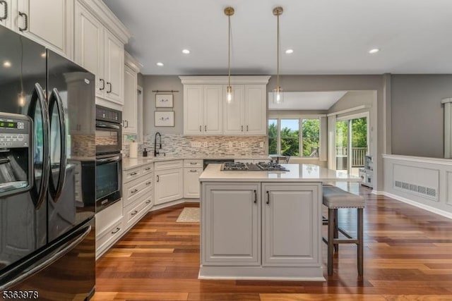 1611 Adams Dr, Greenwich Twp, NJ 08886 - kitchen with black appliances, tasteful backsplash, light countertops, a kitchen island, and dark wood finished floors