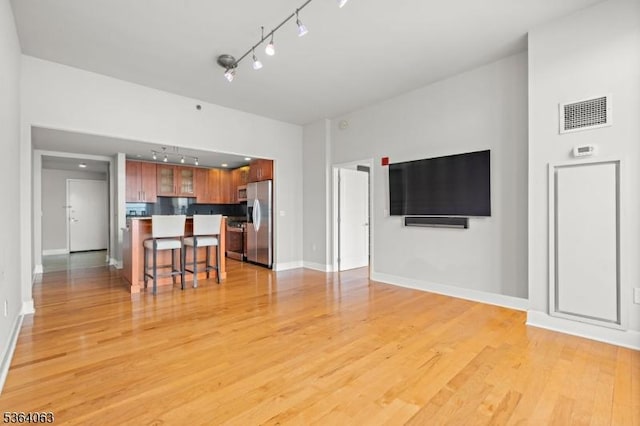 1025 Maxwell Ln Unit 1209, Hoboken City, NJ 07030 - kitchen with stainless steel fridge with ice dispenser, track lighting, a kitchen bar, light wood finished floors, and glass insert cabinets