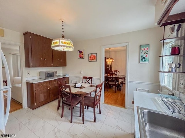 23 Bogle Ave, North Arlington Boro, NJ 07031 - dining area with light marble finish flooring, a wainscoted wall, and a chandelier