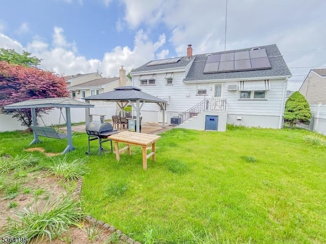 23 Bogle Ave, North Arlington Boro, NJ 07031 - back of property with a gazebo, roof mounted solar panels, a chimney, a shingled roof, and a wall mounted AC