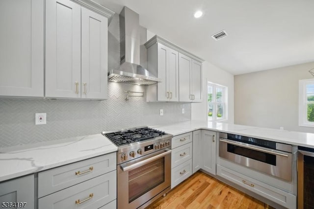 181 Randolph Ave, Mine Hill Twp, NJ 07803 - kitchen featuring stainless steel appliances, wall chimney range hood, light wood finished floors, light stone countertops, and decorative backsplash