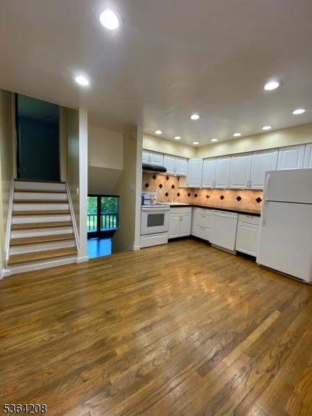 9 Village Way Unit B5, Vernon Twp, NJ 07462 - kitchen with white appliances, dark wood-type flooring, backsplash, dark countertops, and white cabinets