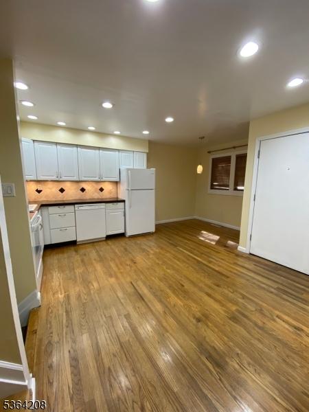 9 Village Way Unit B5, Vernon Twp, NJ 07462 - kitchen featuring white appliances, wood finished floors, white cabinets, decorative backsplash, and recessed lighting