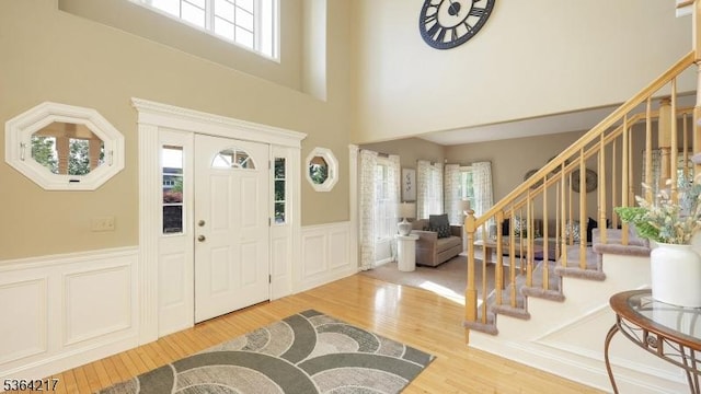 74 Oxford Pl, Hillsborough Twp, NJ 08844 - entrance foyer featuring stairway, wood finished floors, a wainscoted wall, a high ceiling, and a decorative wall