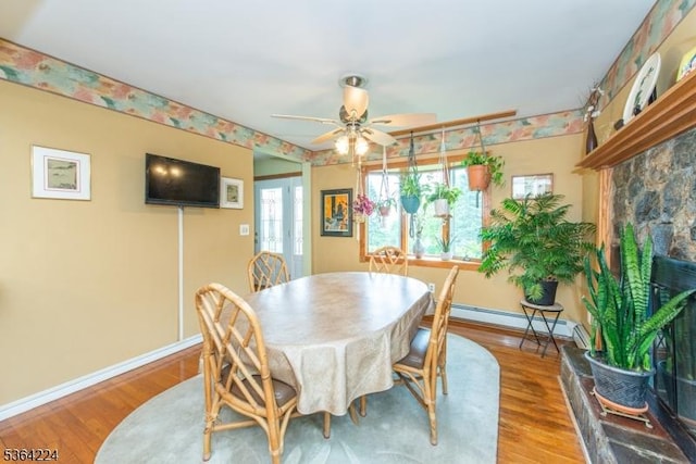 25 Mordaunt Rd, Vernon Twp, NJ 07462 - dining area with wood finished floors, baseboard heating, a ceiling fan, and a fireplace with raised hearth