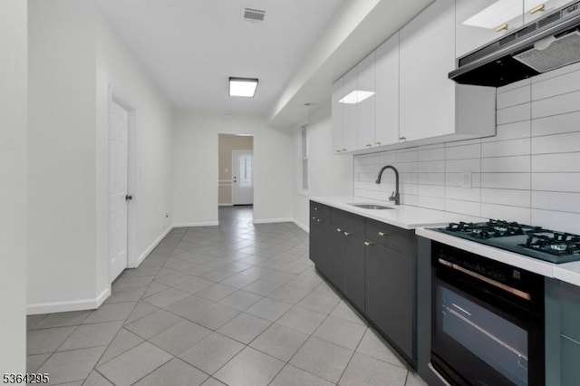 158 Catherine St Unit A/B, Elizabeth City, NJ 07201 - kitchen with under cabinet range hood, black appliances, light countertops, light tile patterned floors, and backsplash