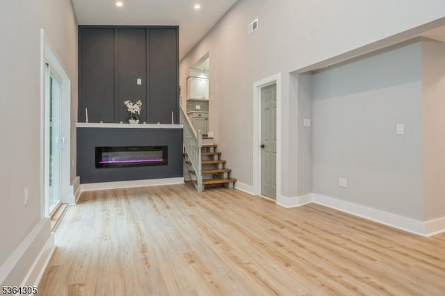 9 Somerset Pl, West Milford Twp, NJ 07480 - unfurnished living room with light wood-type flooring, a glass covered fireplace, recessed lighting, and stairway