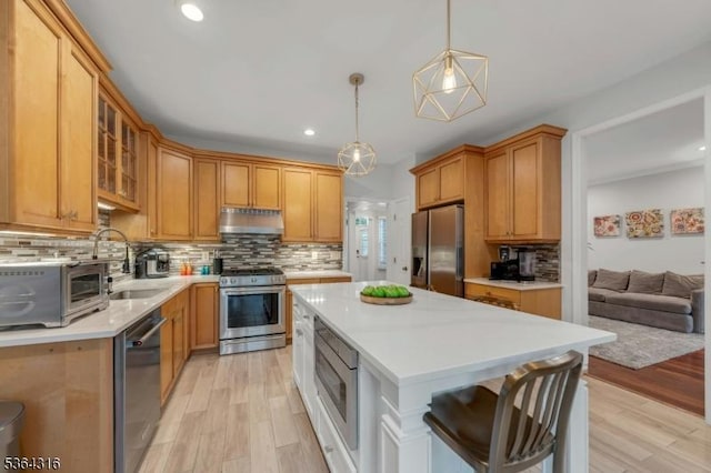 7 Whalen Ct, West Orange Twp, NJ 07052 - kitchen featuring stainless steel appliances, under cabinet range hood, light countertops, light wood finished floors, and backsplash