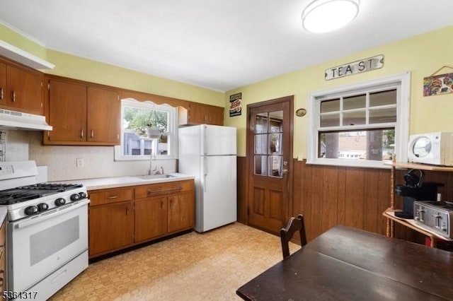 520 Marion St, Bound Brook Boro, NJ 08805 - kitchen featuring white appliances, under cabinet range hood, wainscoting, brown cabinetry, and light floors