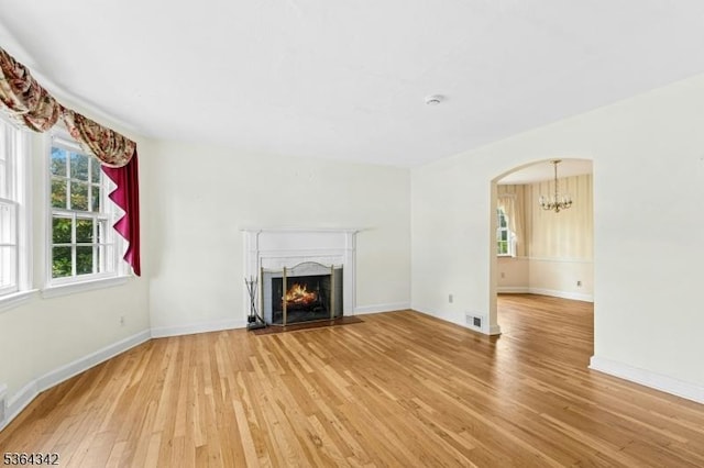 203 Beech St, Cranford Twp, NJ 07016 - unfurnished living room with light wood-style flooring, a chandelier, a fireplace, and arched walkways