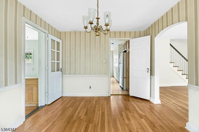 203 Beech St, Cranford Twp, NJ 07016 - unfurnished dining area featuring wallpapered walls, light wood-style floors, a chandelier, stairs, and arched walkways