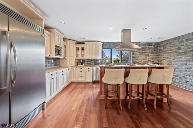 231 Woods Rd, Hillsborough Twp, NJ 08844 - kitchen with built in appliances, cream cabinetry, island range hood, a breakfast bar area, and light wood-type flooring