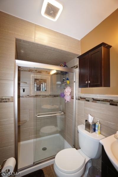 44 Joseph St, Clark Twp, NJ 07066 - bathroom with vanity, a shower stall, and tile walls