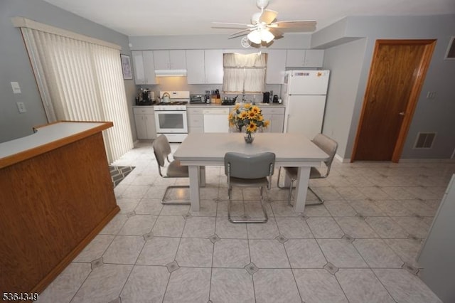 44 Joseph St, Clark Twp, NJ 07066 - kitchen with white appliances, under cabinet range hood, ceiling fan, a breakfast bar area, and white cabinets