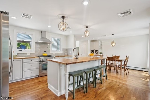 18 Forest Trl, Bernards Twp, NJ 07920 - kitchen featuring appliances with stainless steel finishes, wall chimney exhaust hood, butcher block countertops, backsplash, and an island with sink