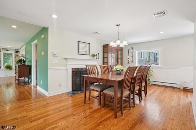 18 Forest Trl, Bernards Twp, NJ 07920 - dining room featuring light wood-style flooring, baseboard heating, a chandelier, a fireplace, and recessed lighting