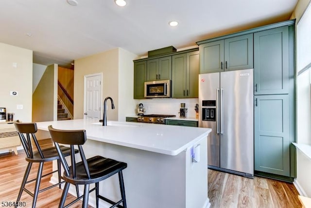 1005 Station Rd, Somerville Boro, NJ 08876 - kitchen with appliances with stainless steel finishes, green cabinets, a kitchen bar, light wood-style floors, and a center island with sink