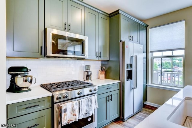 1005 Station Rd, Somerville Boro, NJ 08876 - kitchen with appliances with stainless steel finishes, light countertops, light wood-type flooring, green cabinets, and decorative backsplash