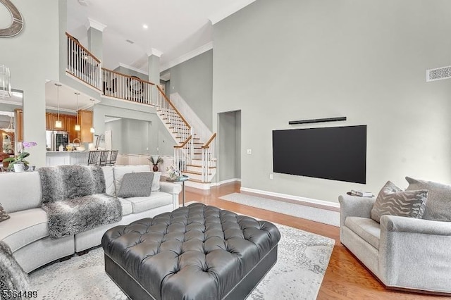 138 Canal Walk Blvd, Franklin Twp, NJ 08873 - living room featuring a high ceiling, stairs, ornamental molding, and light wood-style flooring