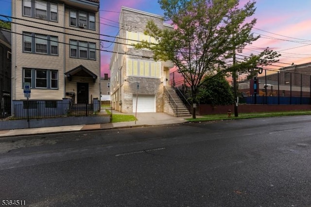 22 Speedway Ave, Newark City, NJ 07106 - property at dusk with an attached garage, stairway, and driveway
